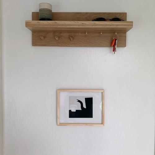 a picture on a white wall with a wooden shelf at Tiny House op de Veluwe Epe in Epe