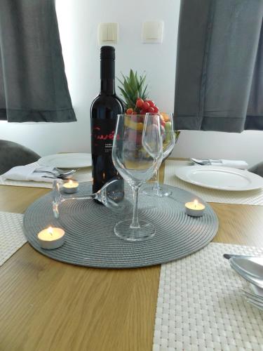 a table with a bottle of wine and two wine glasses at Apartman Naturalis flumen in Otočac