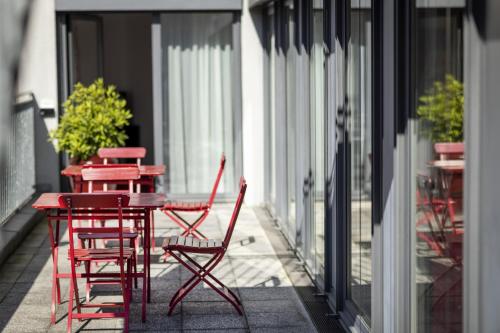 two red chairs and a table on a balcony at ARCOTEL Velvet Berlin in Berlin