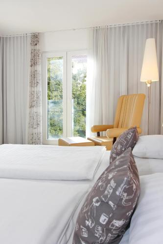 a hotel room with two beds and a chair at ARCOTEL Camino Stuttgart in Stuttgart