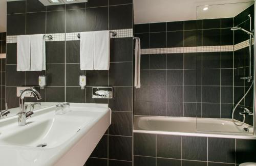 a bathroom with a tub and a sink and a bath tub at ARCOTEL Camino Stuttgart in Stuttgart