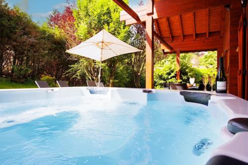 - une piscine avec un parasol et une table dans l'établissement Chalet Les Brimbelles avec Jacuzzi, à Gérardmer
