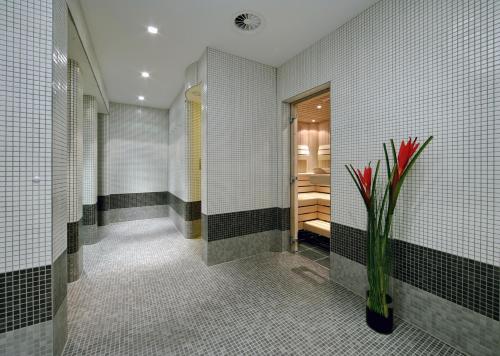 a bathroom with a vase with red flowers in it at ARCOTEL Camino Stuttgart in Stuttgart