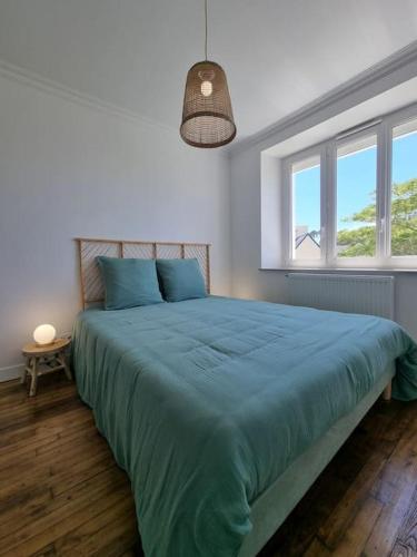 - une chambre dotée d'un grand lit avec des draps bleus et des fenêtres dans l'établissement Maison familiale - 10pers - 3 étoiles - lumineuse et cosy - draps et serviettes inclus - parking - La Torche 9 min, à Saint-Jean-Trolimon