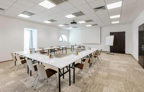 a large room with tables and chairs and a whiteboard at ARCOTEL Camino Stuttgart in Stuttgart
