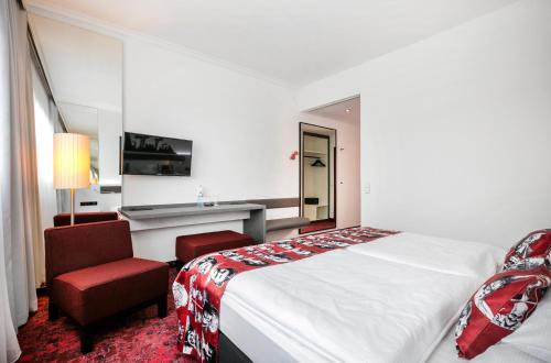 a hotel room with a bed and a chair at ARCOTEL Nike Linz in Linz