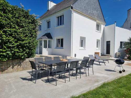 a table and chairs in front of a white house at Maison familiale - 10pers - 3 étoiles - lumineuse et cosy - draps et serviettes inclus - parking - La Torche 9 min in Saint-Jean-Trolimon