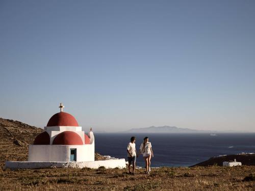 two people standing on top of a hill with a church at Anemelia Hotel Mykonos in Elia Beach