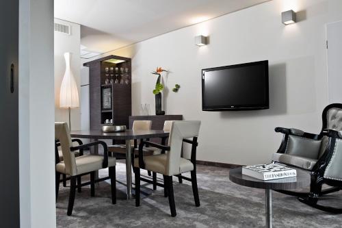 a dining room with a table and chairs and a tv at ARCOTEL John F Berlin in Berlin