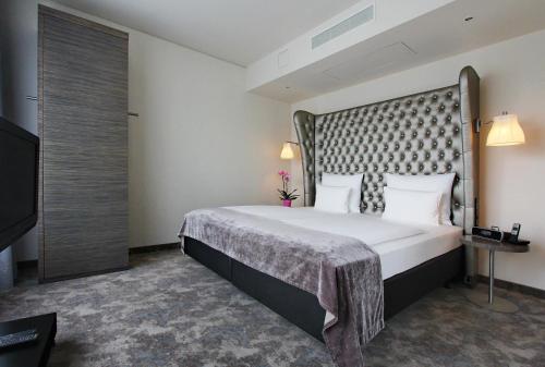 a hotel room with a large bed and a television at ARCOTEL John F Berlin in Berlin