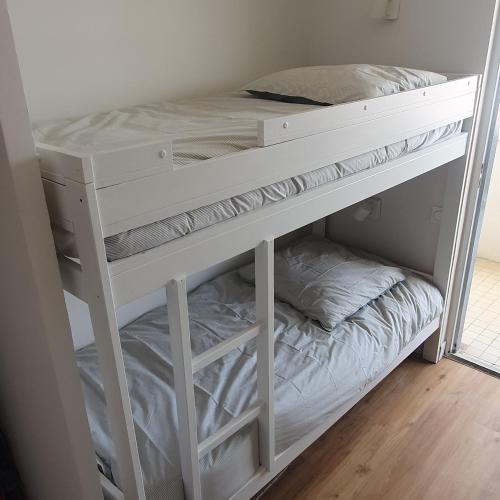 Ce lit superposé blanc se trouve dans un dortoir. dans l'établissement Oceanes appartement vue mer, à Pornichet
