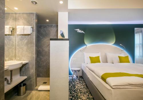 a bedroom with a bed and a bathroom with a sink at ARCOTEL Donauzentrum Wien in Vienna