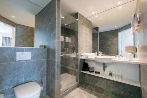 a bathroom with a shower and a toilet and a sink at ARCOTEL Donauzentrum Wien in Vienna