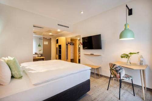 a bedroom with a bed and a desk and a television at ARCOTEL HafenCity Dresden in Dresden