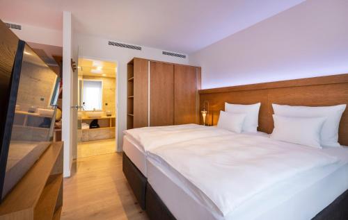 a bedroom with a large white bed and a bathroom at ARCOTEL HafenCity Dresden in Dresden