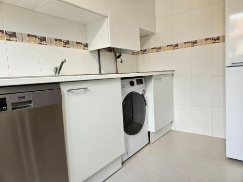 a white kitchen with a washing machine and a sink at Casa Rovacias Comillas C22A01 in Comillas