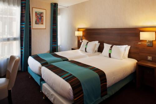 - une chambre avec un grand lit dans une chambre d'hôtel dans l'établissement Holiday Inn Paris Montmartre, an IHG Hotel, à Paris