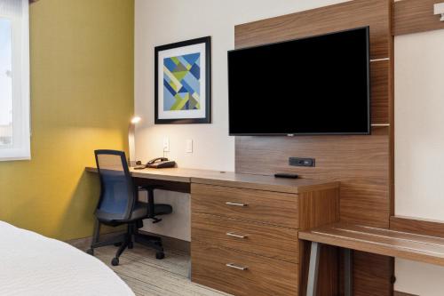 a hotel room with a desk with a television on a wall at Holiday Inn Express & Suites Mountain View Silicon Valley by IHG in Mountain View
