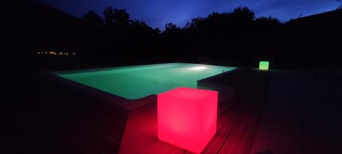 une piscine avec une lumière rose dans le noir dans l'établissement Domaine de Bernassa - Intimité et calme au coeur de 20 hectares de nature, à Saint-Hilaire-de-Lusignan