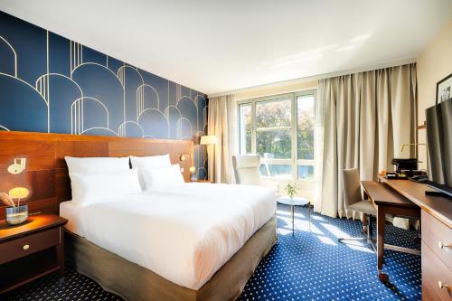 a hotel room with a bed and a desk at Welcome Parkhotel Bochum in Bochum
