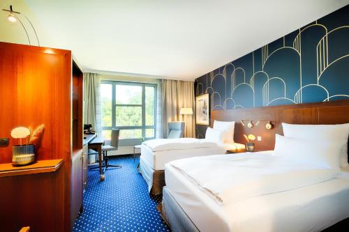 a hotel room with two beds and a desk at Welcome Parkhotel Bochum in Bochum