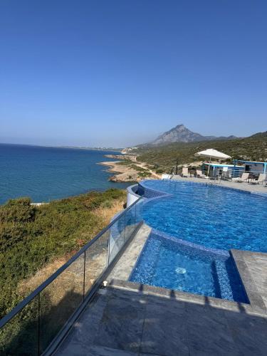 a swimming pool with a view of the ocean at The Rocas Hotel in Kérynia