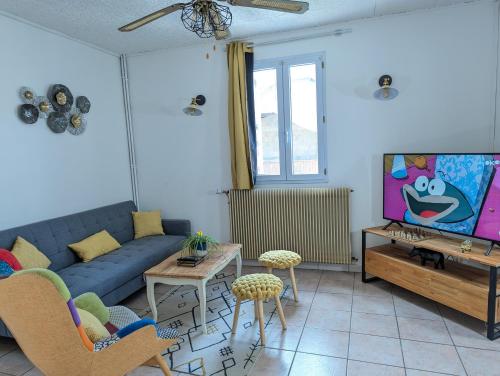 un salon avec un canapé bleu et une télévision dans l'établissement Maison Lefort - 10min Futuroscope, à Beaumont