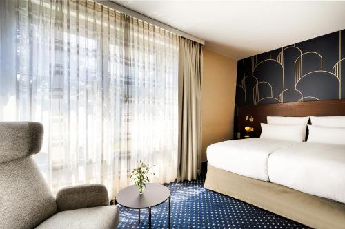 a hotel room with a bed and a chair at Welcome Parkhotel Bochum in Bochum