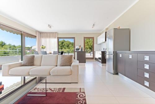 a living room with a white couch and a kitchen at The Residence Aparthotel in Podstrana
