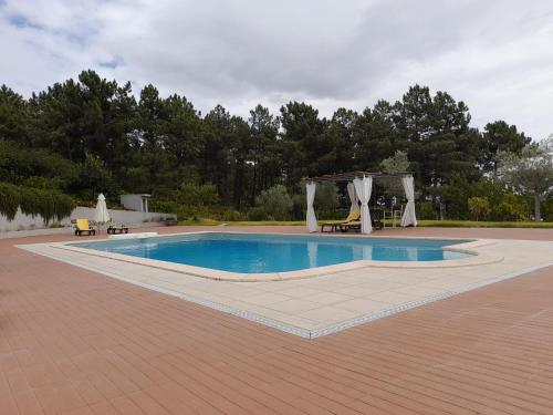 a swimming pool with a pavilion and a picnic table at Quinta Manhas Douro in Provesende