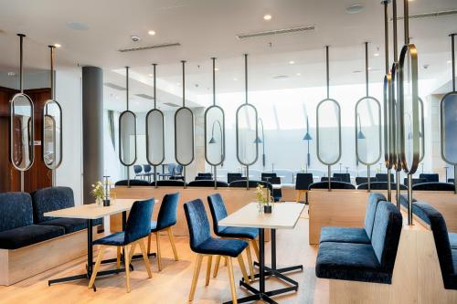 a restaurant with blue chairs and tables and mirrors at Welcome Parkhotel Bochum in Bochum