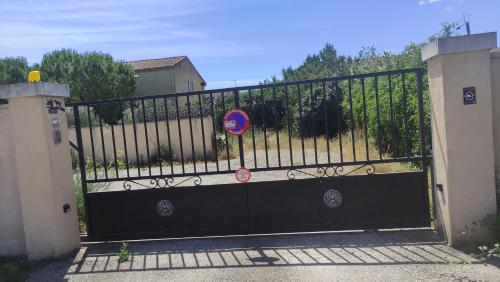 a black gate with a sign on top of it at Au Petit Luberon in Cheval-Blanc