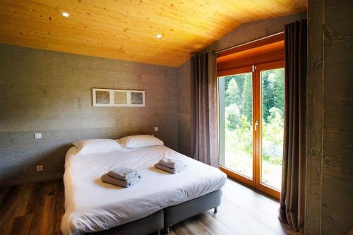 une chambre avec un lit et une grande fenêtre dans l'établissement Original chalet en rondins, l'Ours Canadien, à Xonrupt-Longemer