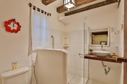 a white bathroom with a toilet and a sink at Pousada Jardim Das Margaridas in Trancoso