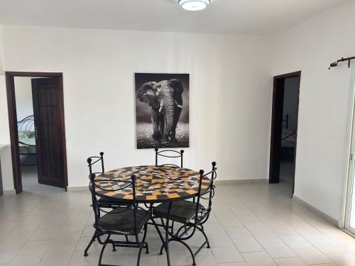 a table and chairs in a room with a picture of an elephant at RELAX PARC Mboro in Mboro
