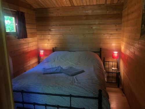 a bedroom with a bed in a wooden cabin at Domaine La Faix, Gite la Forestière in Saint-Plaisir