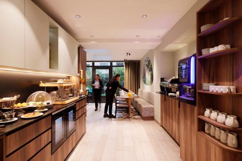 two people standing in a kitchen with a counter at Hotel Eden in Paris
