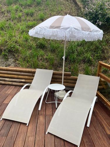 two white chairs and an umbrella on a deck at Casa Rina in Gignod