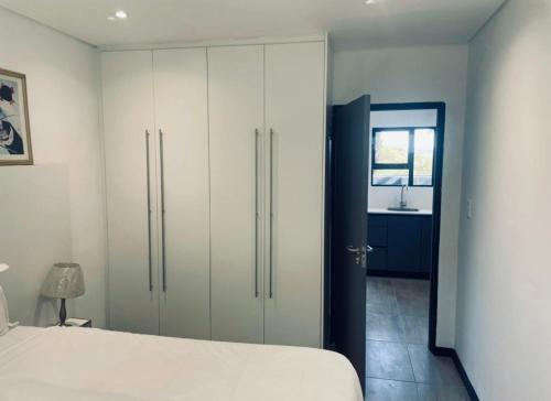 a bedroom with a white bed and a bathroom at No 6 On Cladon # Jadde Apartments in Chartwell