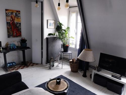 a living room with a couch and a tv at Beau studio à Fontenay sous bois in Fontenay-sous-Bois