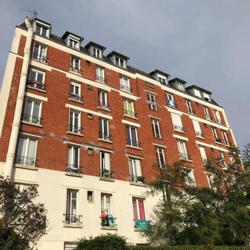 un grand bâtiment en briques rouges avec beaucoup de fenêtres dans l'établissement Beau studio à Fontenay sous bois, à Fontenay-sous-Bois