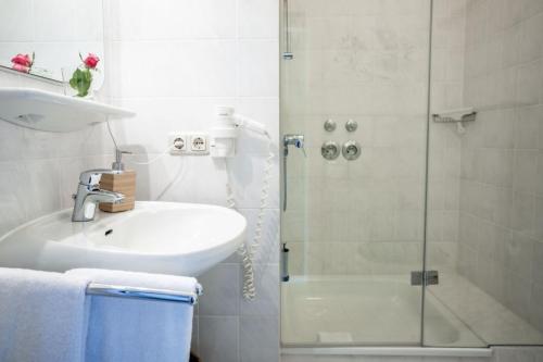 a white bathroom with a sink and a shower at Herrenhaus Appartement 4 in Lüdersburg