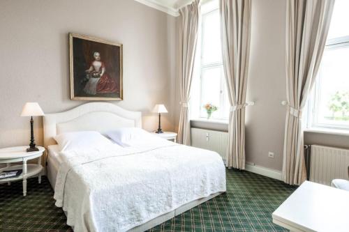 a bedroom with a white bed and a painting on the wall at Herrenhaus Appartement 4 in Lüdersburg