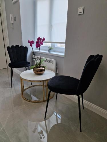 twee stoelen en een tafel met een vaas met bloemen erop bij Luxury Apartment Paper in Zagreb