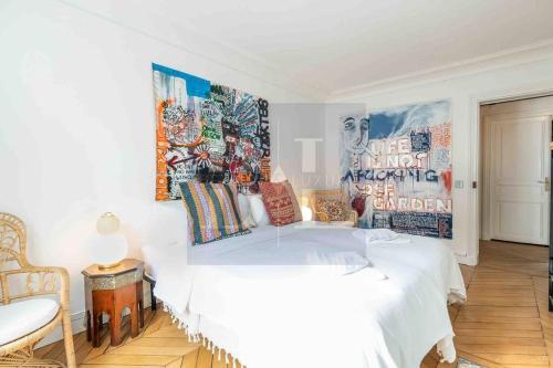 - une chambre avec un lit blanc et des affiches sur le mur dans l'établissement Dauphine Saint Germain 6th arr 2bedrooms, à Paris