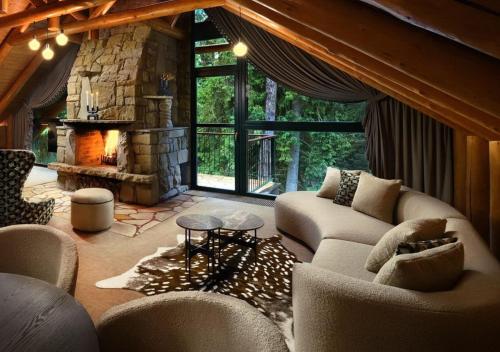 a living room with couches and a stone fireplace at Hotel Tri Studničky - Adult friendly in Demanovska Dolina