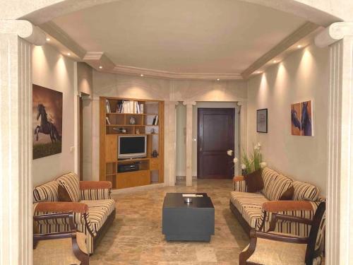 a living room with a couch and chairs and a tv at Spacious Apart, 2-min to beach & Old Souk in Jbeil