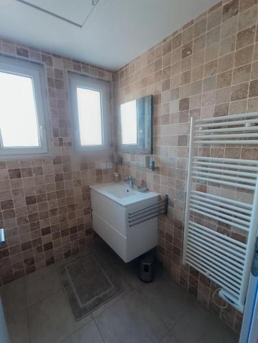 La salle de bains est pourvue d'un lavabo, d'un miroir et de fenêtres. dans l'établissement LE CAVAOU, à Mérindol