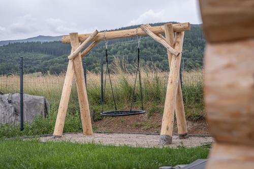 a wooden swing set in the middle of a field at Zrub Šumiac in Šumiac