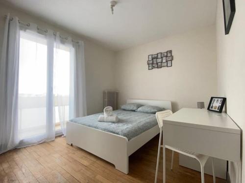 Un dormitorio blanco con una cama y un escritorio. en Joli T4 avec balcon, place de parking - Oradou, en Clermont-Ferrand